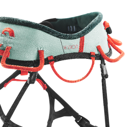 A close up of the haul loop of a womans session harness by Wild Country in light green and orange design.