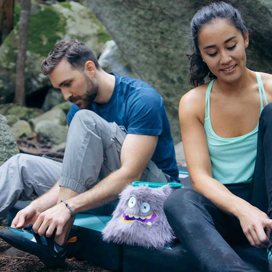 8b+ chalk bucket hector inbetween two climbers on boulder pad putting on climbing shoes