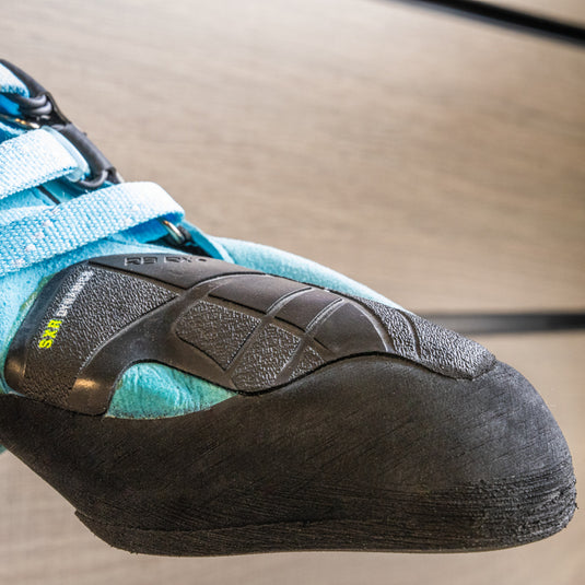 A close up Tenaya Indalo toe box, resting on black wall hook against metallic background.