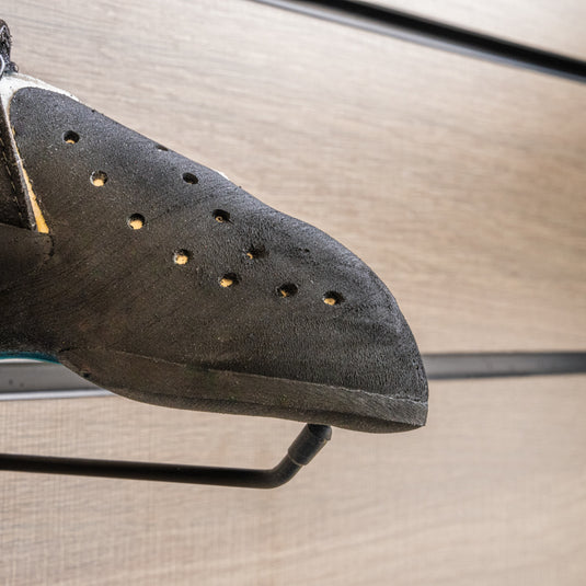 A close up Scarpa Drago LV toe box, resting on black wall hook against metallic background.