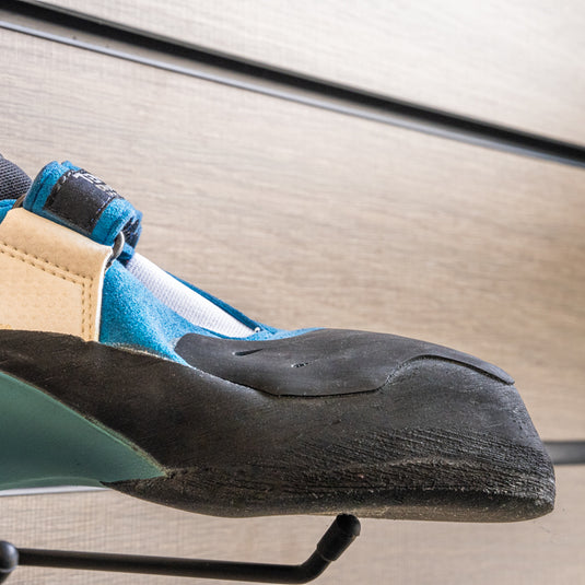 A close up Tenaya Mastia toe box, resting on black wall hook against metallic background.