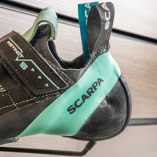A close up of Scarpa Instinct VS WMN heel, resting on black hook against metallic background.