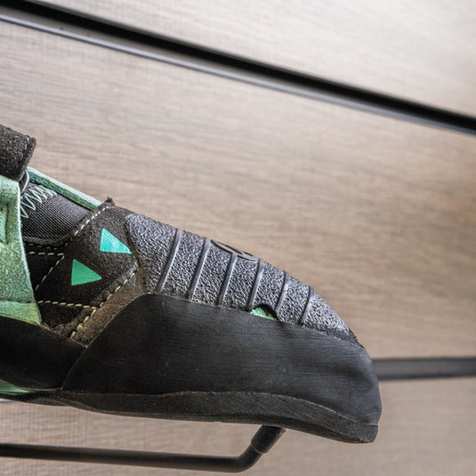 A close up Scarpa Instinct VS WMN toe box, resting on black wall hook against metallic background.