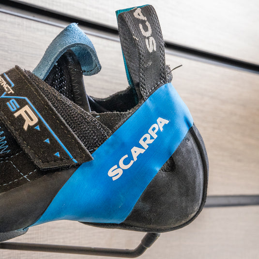 A close up of Scarpa INSTINCT VSR heel, resting on black hook against metallic background.