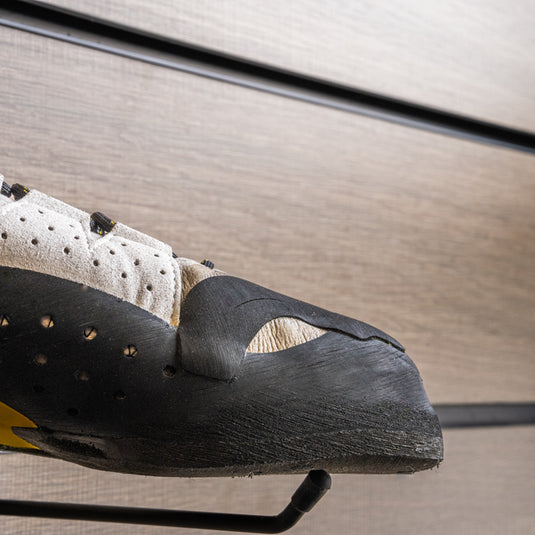 A close up Tenaya Tarifa toe box, resting on black wall hook against metallic background.