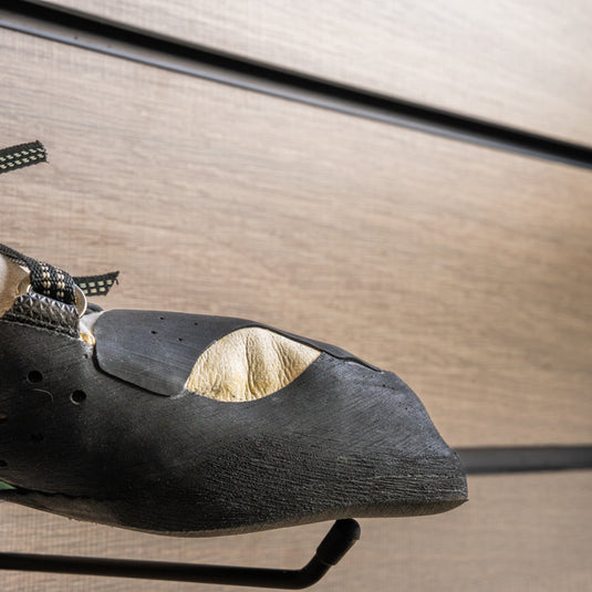 A close up Tenaya Oasi lv toe box, resting on black wall hook against metallic background.