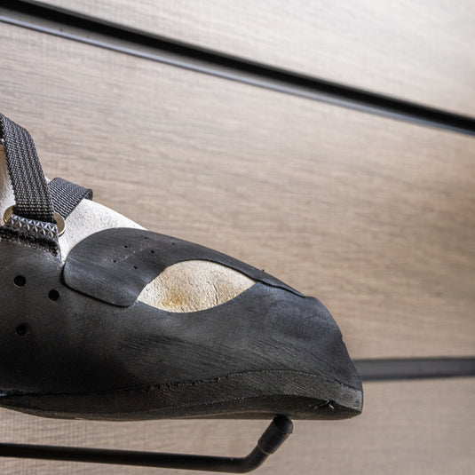 A close up Tenaya Oasi toe box, resting on black wall hook against metallic background.