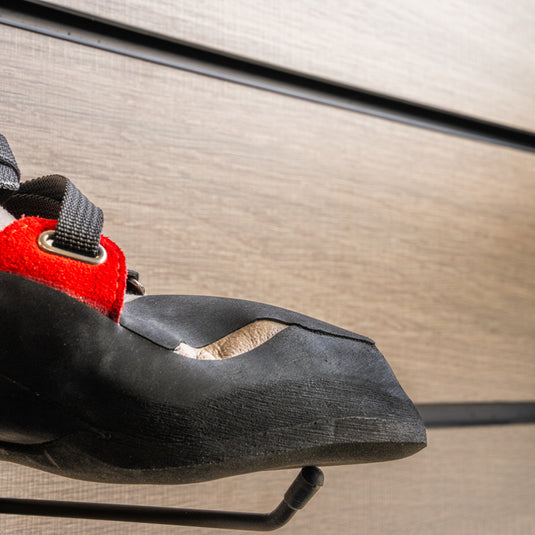 A close up Tenaya Iati toe box, resting on black wall hook against metallic background.