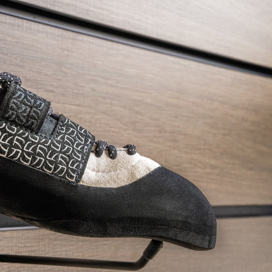A close up La Sportiva Katana lace women toe box, resting on black wall hook against metallic background.