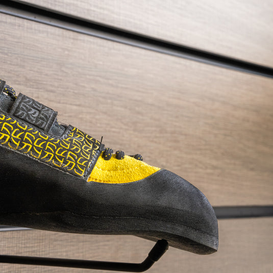 A close up La Sportiva katana Lace toe box, resting on black wall hook against metallic background.