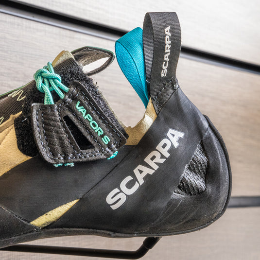 A close up Scarpa Vapour S Women heel, resting on black wall hook against metallic background.