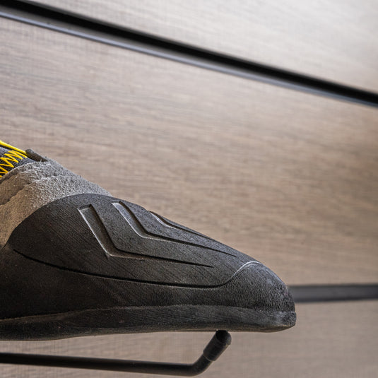 A close up Scarpa Vapour S toe box, resting on black wall hook against metallic background.