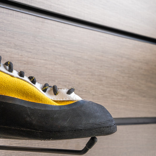 A close up Tenaya Masai toe box, resting on black wall hook against metallic background.