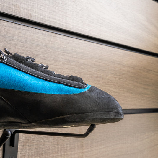 A close up Unparallel Up lace toe box, resting on black wall hook against metallic background.