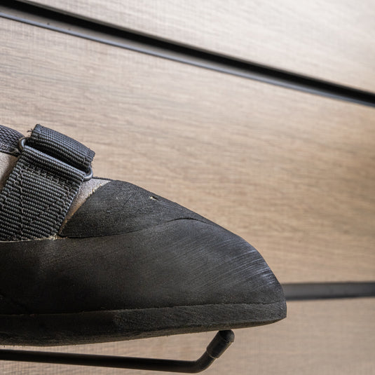 A close up Unparallel Up Rise toe box, resting on black wall hook against metallic background.