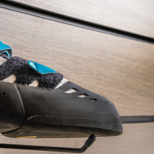 A close up La Sportiva Tarantula Boulder womens toe box, resting on black wall hook against metallic background.