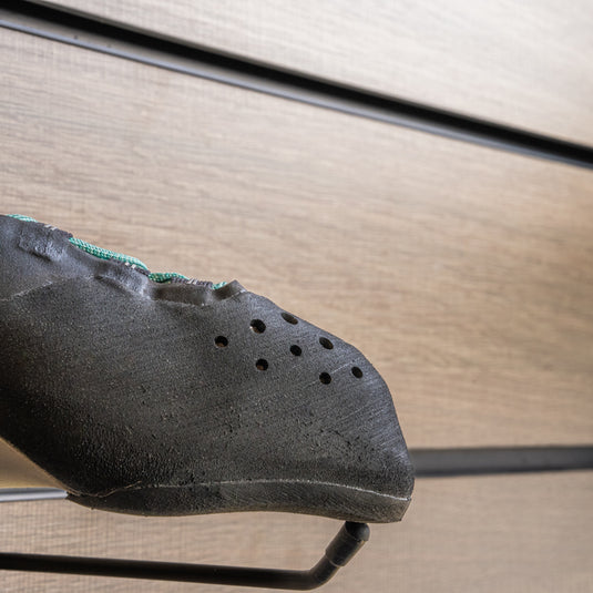 A close up Scarpa Veloce Lace WMN toe box, resting on black wall hook against metallic background.