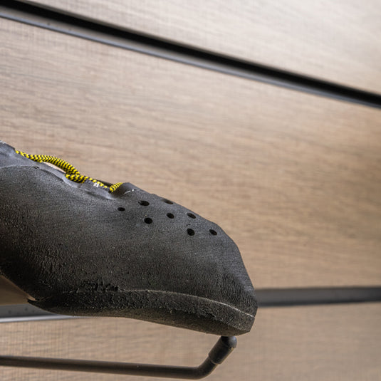A close up Scarpa Veloce Lace toe box, resting on black wall hook against metallic background.