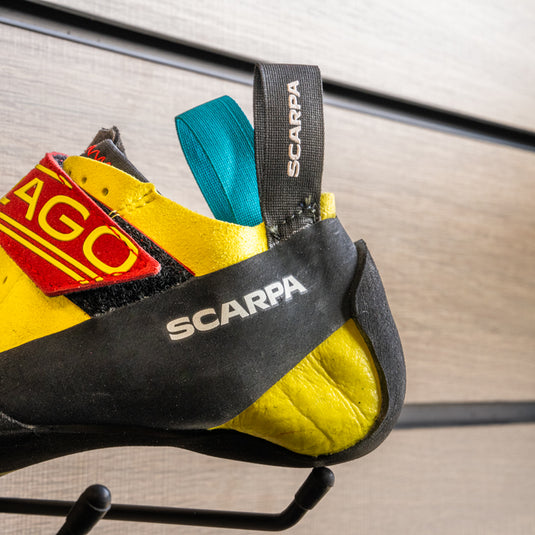A close up of Scarpa drago kids heel, resting on black hook against metallic background.