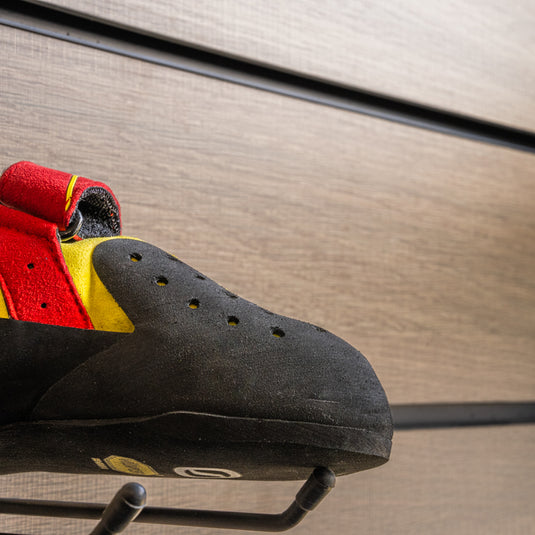 A close up Scarpa Drago Kids toe box, resting on black wall hook against metallic background.