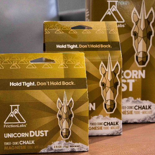 Three gold packages of Friction Labs Chalk - Unicorn Dust - featuring a geometric unicorn logo with the tag line "Hold Tight. Don't Hold Back"