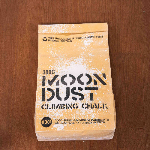 300g moon dust climbing chalk in a brown paper package displayed lay down on wooden surface.