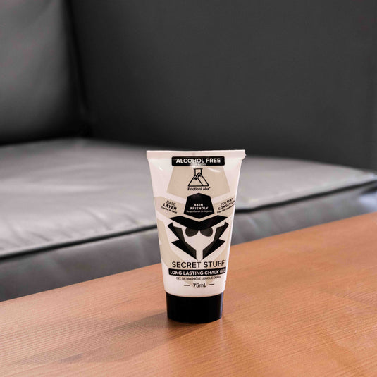 One 75ml tube of Friction Labs Secret Stuff Liquid Chalk Alcohol-Free in black and white design. The tube is displayed on a wooden surface.
