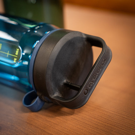 Side profile of a blue HyrdraPak Recon Water Bottle Lid displaying handle and clip and carry design.