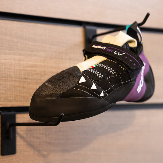 A close up Scarpa Instinct VSR LV toe box, resting on black wall hook against metallic background.