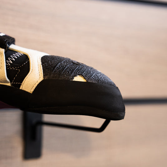 A close up Scarpa Instinct VSR LV toe box, resting on black wall hook against metallic background.