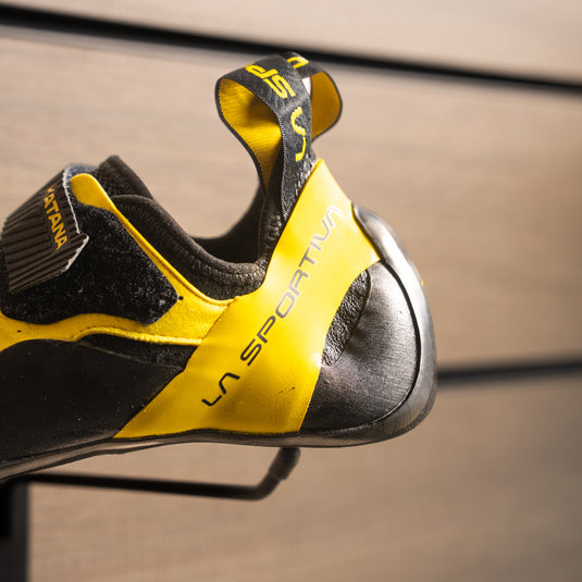A close up of La Sportiva Katana velcro heel, resting on black hook against metallic background.