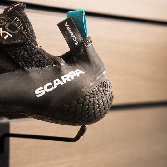 A close up of Scarpa Drago XT textured heel, resting on black hook against metallic background.