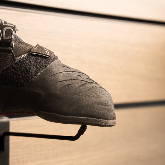 A close up Scarpa Drago XT toe box, resting on black wall hook against metallic background.