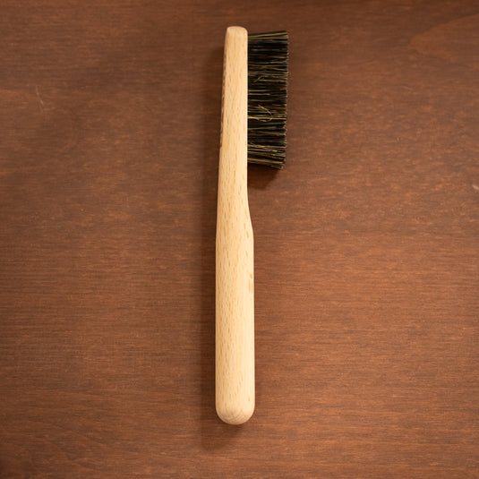 One wooden Climb Lab climbing brush resting on a wooden surface