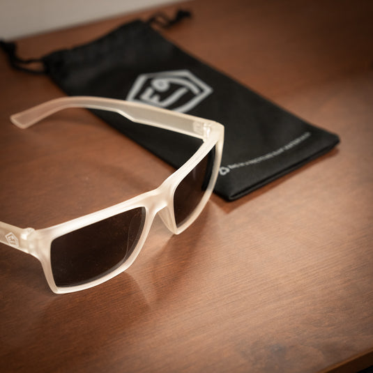 E9 Sunglasses - "Paul" laid on wooden surface with sunglasses bag with e9 logo on in black in blurredbackground