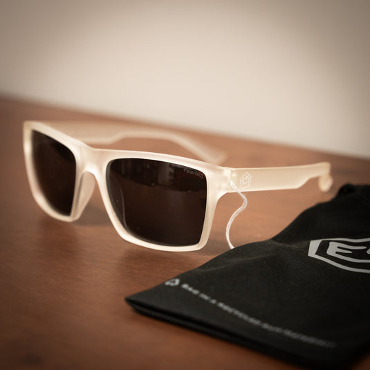 E9 Sunglasses - "Paul" laid on wooden surface with sunglasses bag with e9 logo on in black in blurredbackground