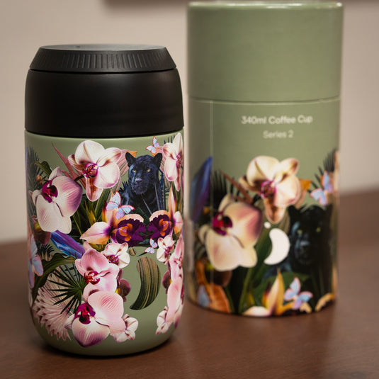 A reusable chilly's coffee cup with vibrant floral designs and a hidden black panther, beside its matching packaging.