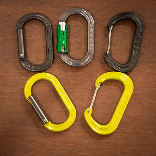 five varients of the DMM XSRE Mini Carabiner - straight gate in matt gray and in lime, wire gate in matt gray and in lime, locksafe in titanium and green