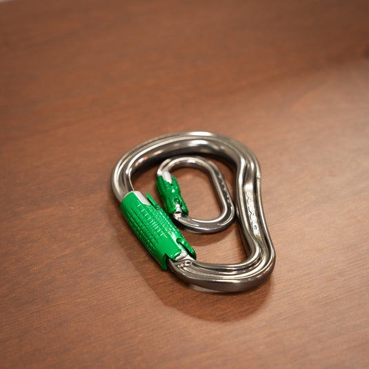 mini locksafe carabiner inside locksafe DMM phantom carabiner - both  in titanium and green, laid on wooden surface