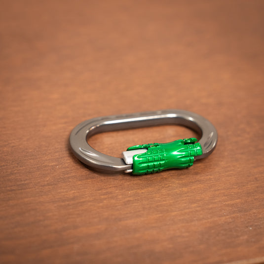 mini locksafe carabiner in titanium and green, laid on wooden surface