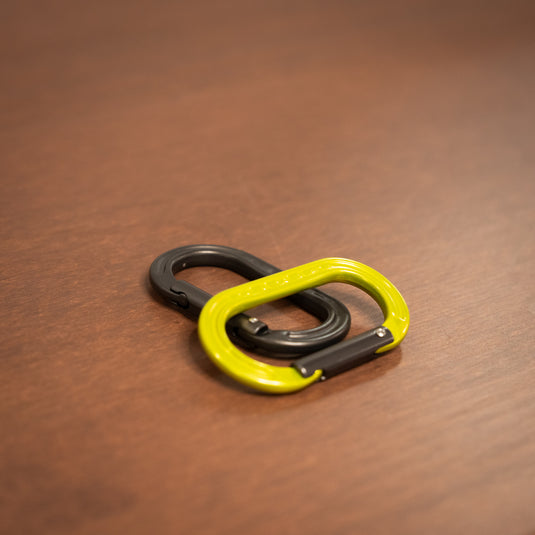 straight gate DMM XSRE Mini Carabiner in matt gray and in lime laid on wooden surface