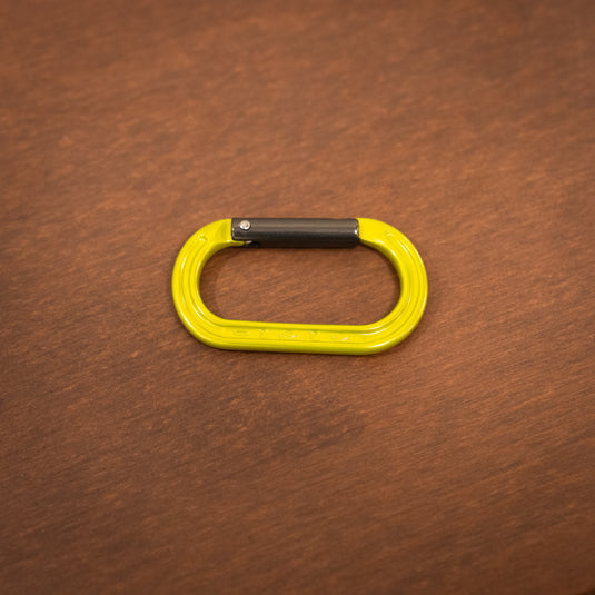 Straight gate mini carabiner in lime laid on wooden surface