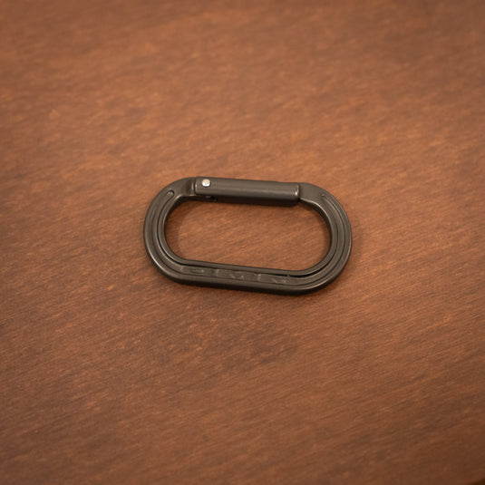Straight gate mini carabiner in Matt Gray laid on wooden surface