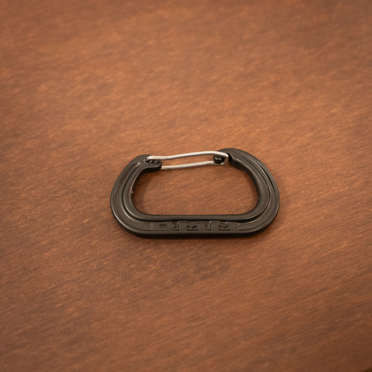 Wire gate mini carabiner in Matt Gray laid on wooden surface
