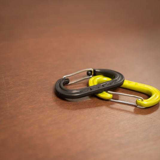 Wiregate DMM XSRE Mini Carabiner in matt gray and in lime laid on wooden surface