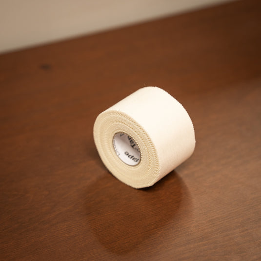Thick white fabric roll of Beta Climbing Tape displayed on wooden surface.