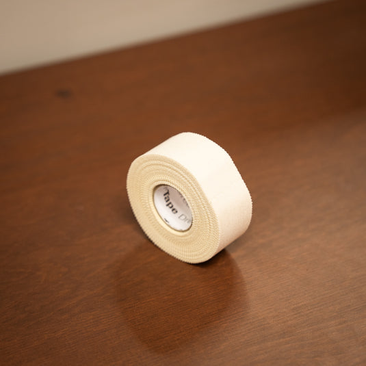 Thinner white fabric roll of Beta Climbing Tape displayed on wooden surface.