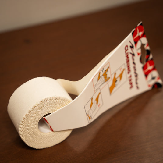 Roll of Metolius Climbing Tape on a wooden background. Usage instructions are on the packaging.