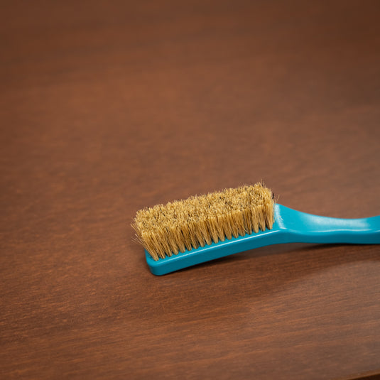 8b+ save the ocean climbing brush in blue resting on a wooden surface.