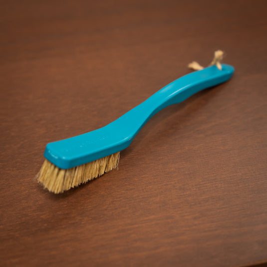 8b+ save the ocean climbing brush in blue resting on a wooden surface.